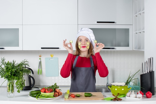 Free photo front view female chef in apron putting cucumber slices on her face