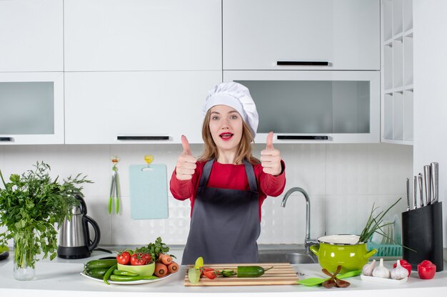 Женщина-шеф-повар в шляпе повара, подняв палец вверх, вид спереди