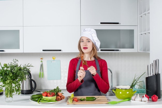 Front view female chef in cook hat holding wooden spoons