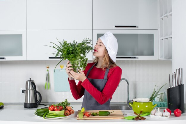 Front view female chef in cook hat smelling greens