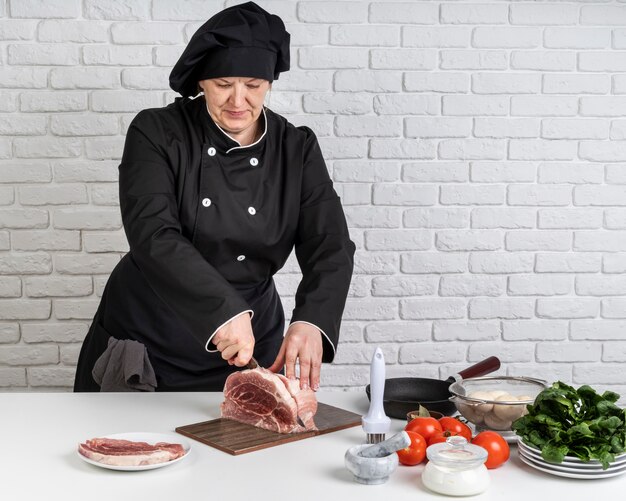 Front view of female chef cutting meat