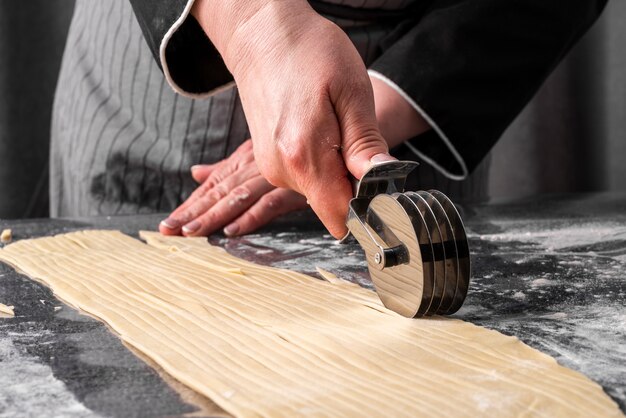 Front view of female chef cutting though into strips