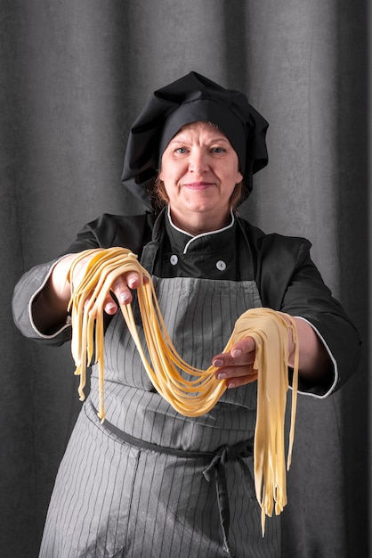 Free photo front view of female chef holding fresh pasta