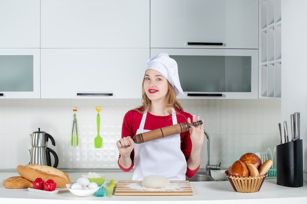 Free photo front view female chef holding up rolling pin in the kitchen