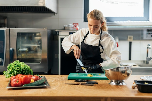 Front view of female chef in the kitchen slicing vegetables