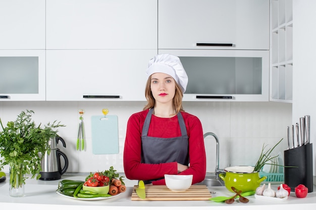 Front view female chef in uniform crossing hands in kitchen