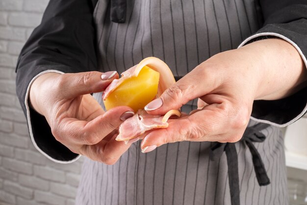 Front view of female chef wrapping bacon around fruit