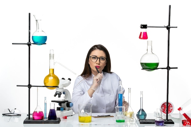 白い医療スーツを着た女性化学者の正面図白い背景の科学ウイルス共同パンデミックラボで作業し、メモを書いています