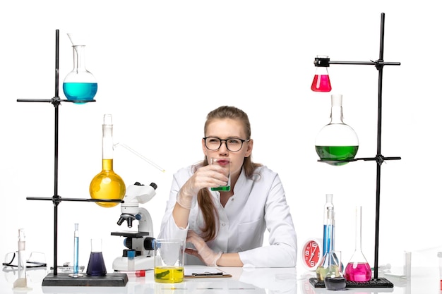 Front view female chemist in medical suit checking smell of solution on white background chemistry pandemic health covid