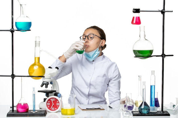 흰색 배경 스플래시 실험실 바이러스 화학 COVID에 마스크 마시는 솔루션 의료 소송에서 전면보기 여성 화학자