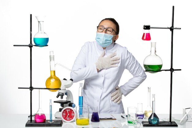 Front view female chemist in medical suit with mask having heartache on white background virus chemistry lab covid- splash