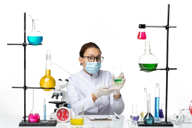밝은 흰색 배경 스플래시 실험실 바이러스 화학 covid-에 솔루션을 들고 마스크와 의료 소송에서 전면보기 여성 화학자
