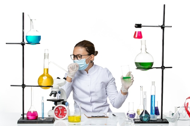 Front view female chemist in medical suit with mask holding solution on white background splash lab virus chemistry covid-