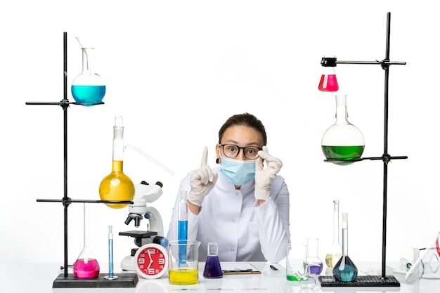 白い背景に座っているマスクと医療スーツの正面図女性化学者ウイルス化学実験室covidスプラッシュ