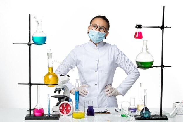 Front view female chemist in medical suit with mask thinking on a white background virus chemistry lab covid- splash