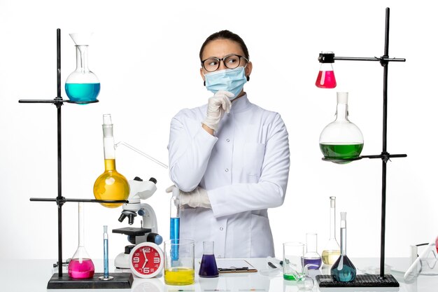 Front view female chemist in medical suit with mask thinking on white background virus chemistry lab covid- splash