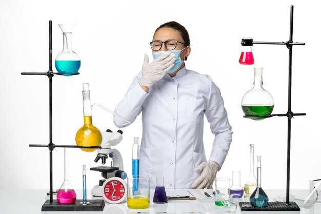 Вид спереди женщина-химик в медицинском костюме с маской, зевая на белом фоне Лаборатория химии вирусов covid- splash