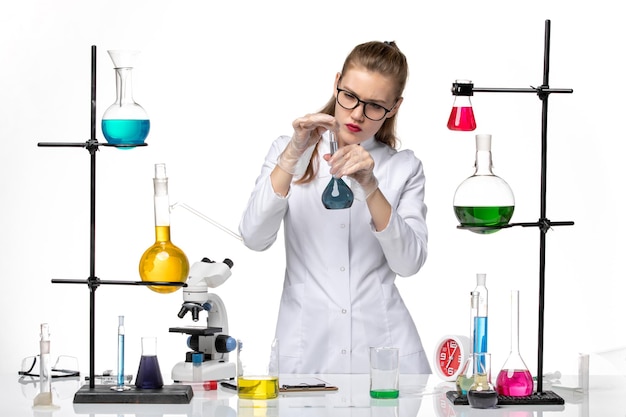 Вид спереди женщина-химик в медицинском костюме в рабочем процессе с растворами на белом фоне химический пандемический вирус covid
