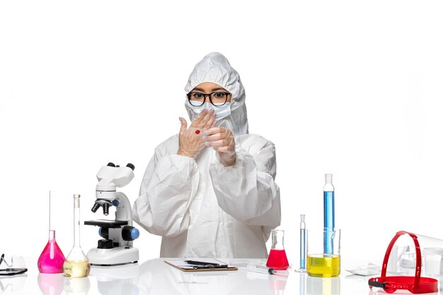 Front view female chemist in special protective suit checking samples with microscope on white desk virus chemistry covid- pandemic health