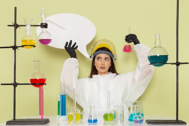 Вид спереди женщина-химик в специальном защитном костюме с большим белым знаком на зеленой поверхности