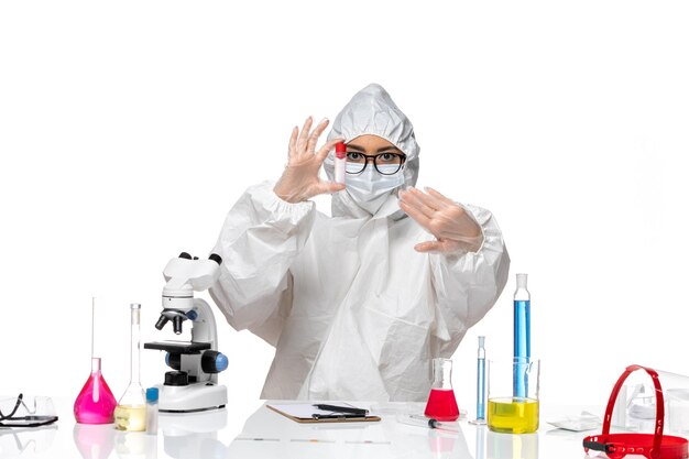 Front view female chemist in special protective suit holding empty flask on white desk virus health chemistry covid-