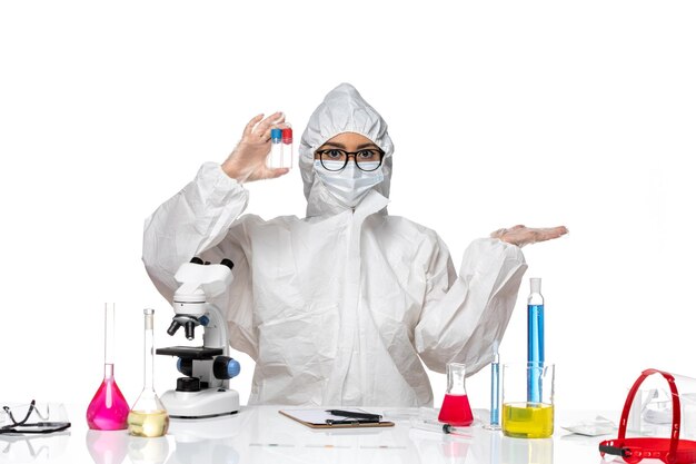 ライトホワイトの背景に空のフラスコを保持している特別な防護服の正面図女性化学者ウイルス健康化学covid