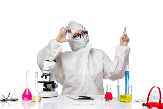 Front view female chemist in special protective suit holding empty flasks on white background health virus chemistry covid