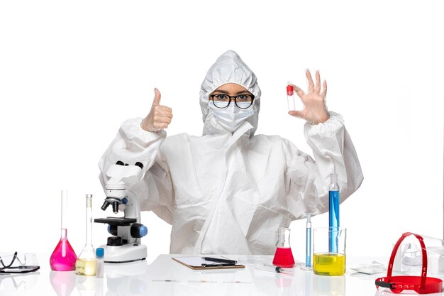 Front view female chemist in special protective suit holding flask on a white background virus health chemistry covid-