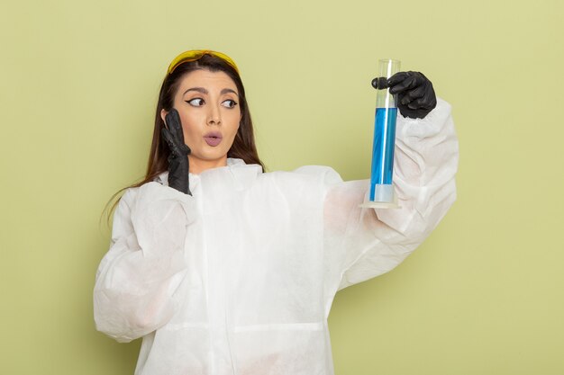 Free photo front view female chemist in special protective suit holding flask with solution on light-green surface