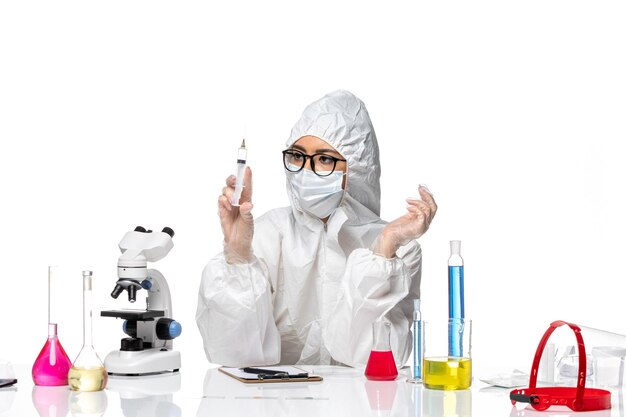 Вид спереди женщина-химик в специальном защитном костюме, держащая инъекцию на белом фоне, пандемия химического вируса ковид-вируса