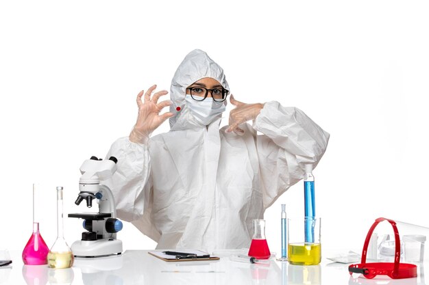 ライトホワイトの背景にサンプルを保持している特別な防護服を着た女性化学者の正面図化学covidウイルスパンデミック