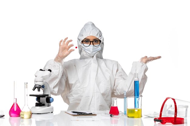 Front view female chemist in special protective suit holding sample on light white background chemistry covid virus pandemic