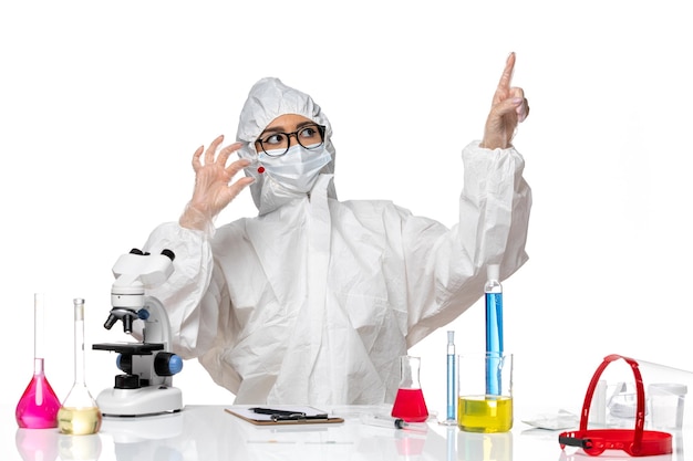 Front view female chemist in special protective suit holding sample on the white background chemistry covid virus pandemic