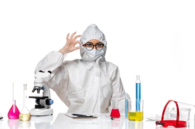 Front view female chemist in special protective suit holding sample on white background chemistry covid virus pandemic