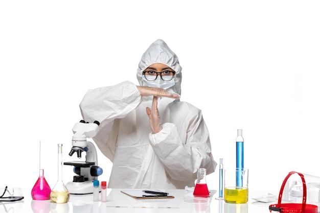 Front view female chemist in special protective suit showing t sign on white background covid- chemistry virus lab