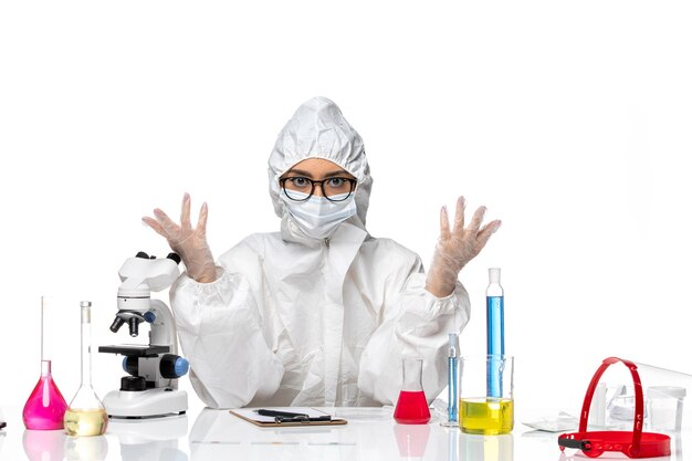 흰색 배경 화학 covid 바이러스 유행병에 솔루션과 함께 앉아 특수 보호 복에 전면보기 여성 화학자