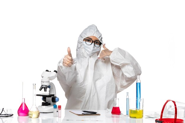 Front view female chemist in special protective suit working posing on the white background covid- chemistry virus lab