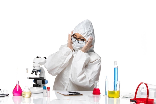 Front view female chemist in special protective suit working with different solutions on white background covid chemistry virus lab