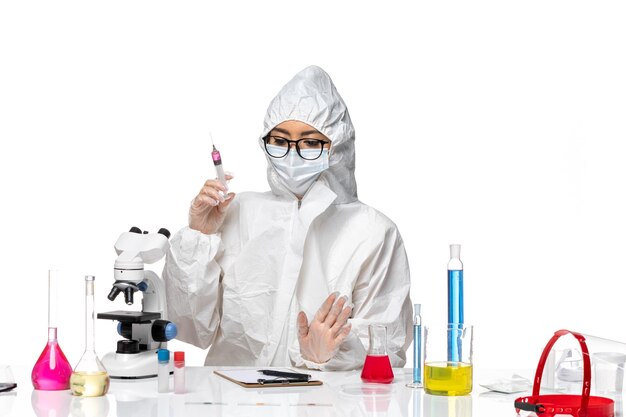 Front view female chemist in special protective suit working with injections on white desk covid chemistry virus lab