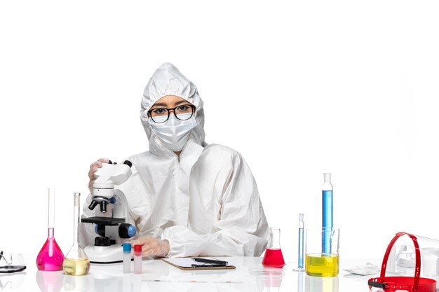 Front view female chemist in special protective suit working with microscope on white background covid chemistry virus lab