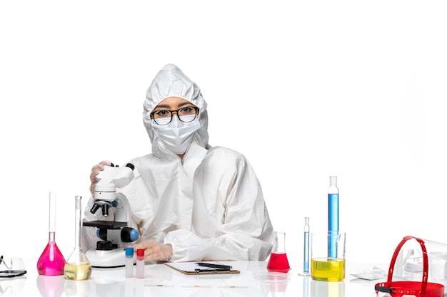 Front view female chemist in special protective suit working with microscope on white background covid chemistry virus lab