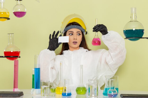 薄緑色の表面で溶液を扱う特別な防護服を着た女性化学者の正面図