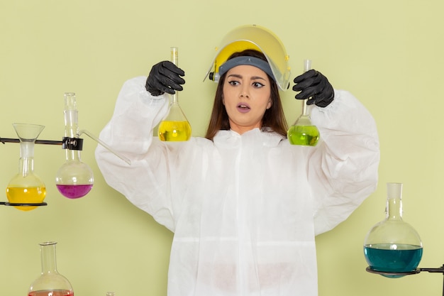 Free photo front view female chemist in special protective suit working with solutions on green desk