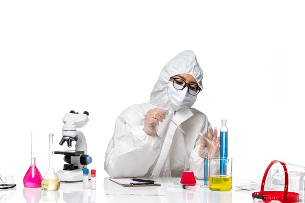밝은 흰색 배경 바이러스 covid 화학 실험실에서 솔루션으로 작업하는 특수 보호 복의 전면보기 여성 화학자