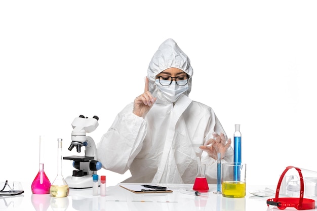 白い背景のcovid化学ウイルスラボでソリューションを使用して作業している特別な防護服の正面図の女性化学者
