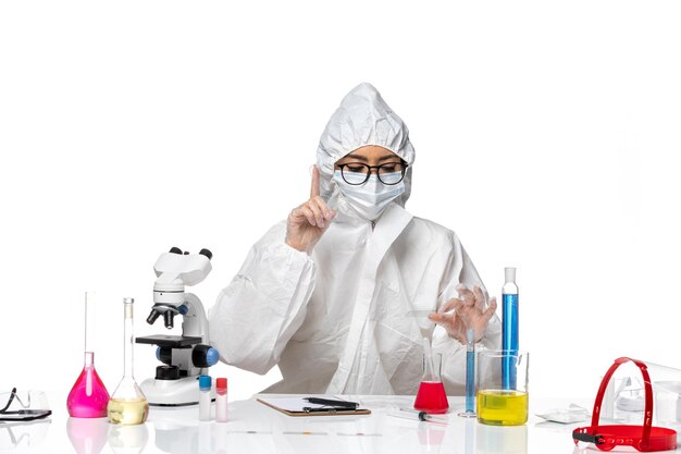 白い背景のcovid化学ウイルスラボでソリューションを使用して作業している特別な防護服の正面図の女性化学者