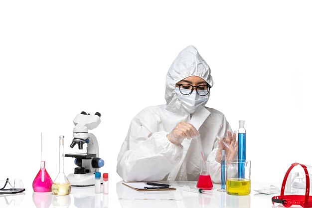 Front view female chemist in special protective suit working with solutions on white background health virus covid chemistry