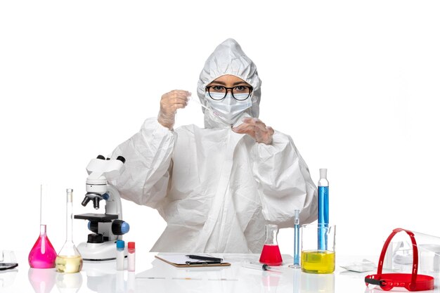 Front view female chemist in special protective suit working with solutions on the white background virus covid chemistry lab
