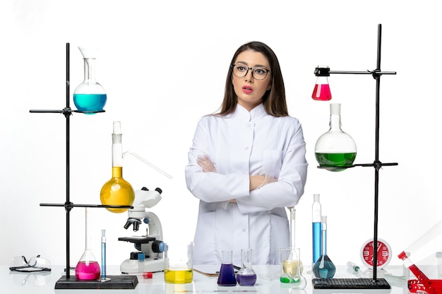 Free photo front view female chemist in sterile medical suit standing around table with solutions on white background virus disease covid- lab science