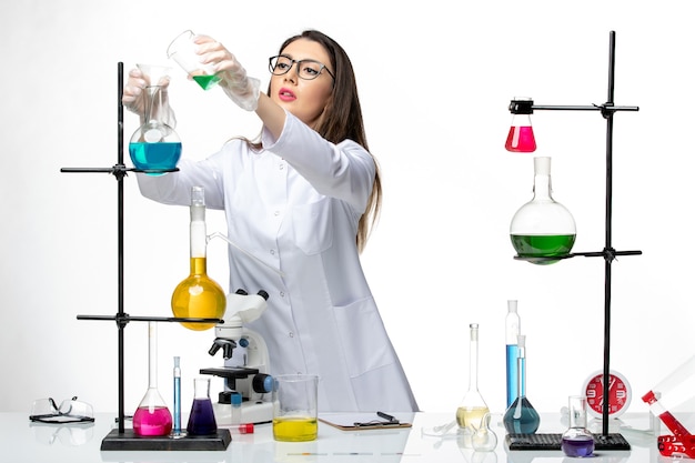 Вид спереди женщина-химик в стерильном медицинском костюме, работающая с растворами на белом фоне, лабораторный вирус covid - наука о пандемии